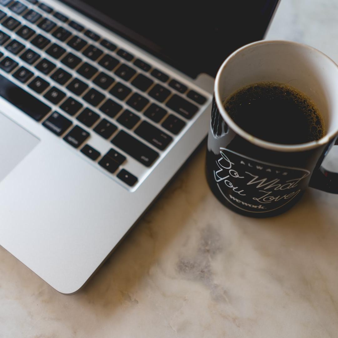 coffee in mug beside MacBook Pro